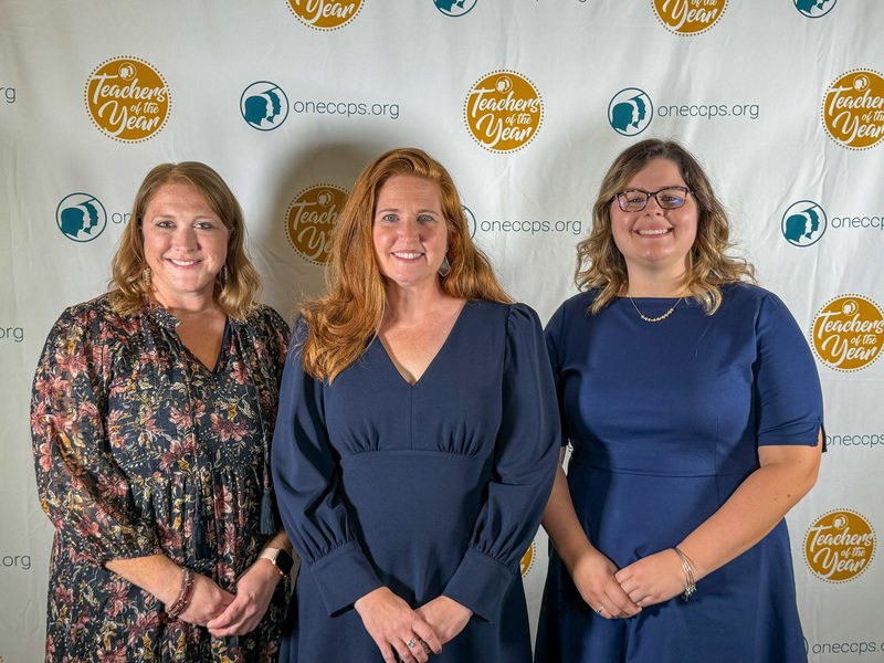 Three women smiling in front of backdrop