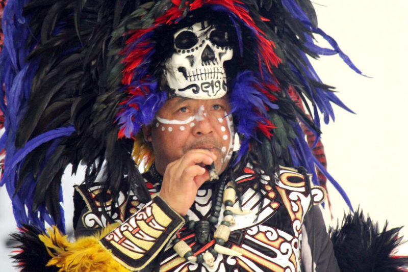 Man in colorful plumage with skull mask