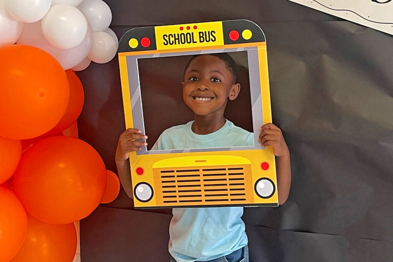 Young student smiling through school bus cutout