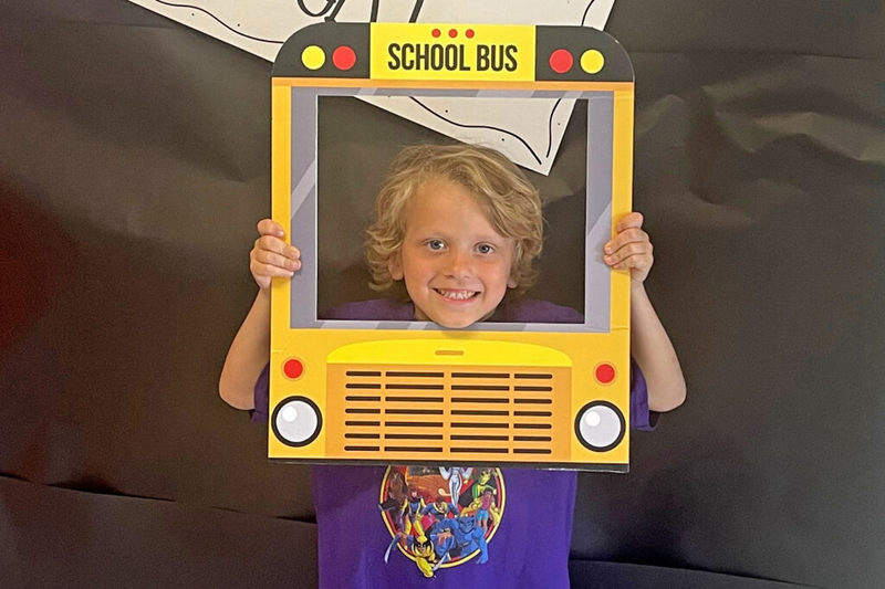 Young student smiling through school bus cutout