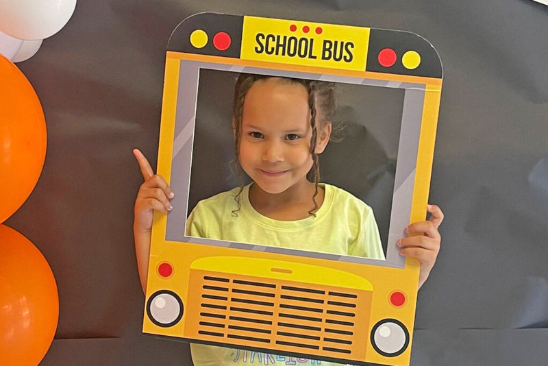 Young student smiling through school bus cutout