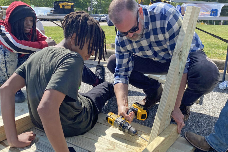 Students watching man drill into lumber