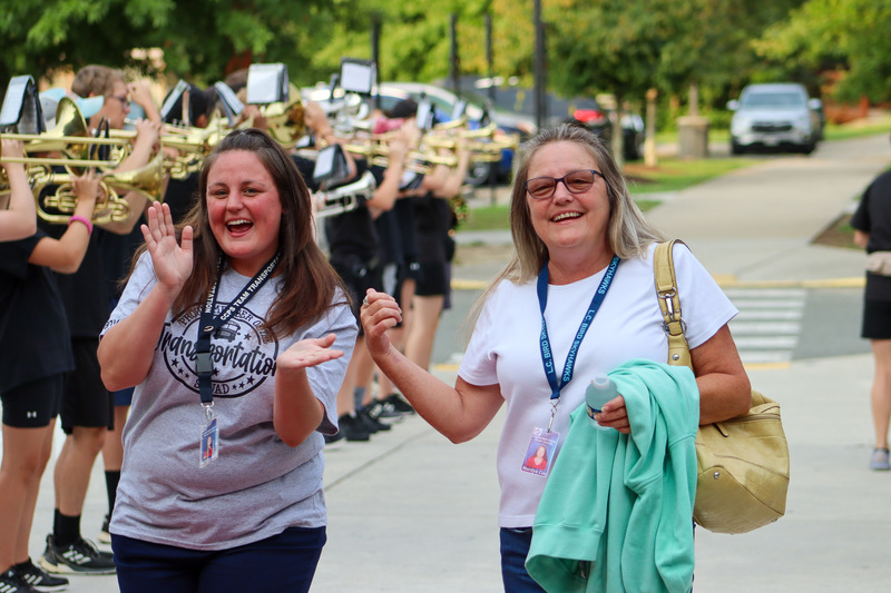 Two women smiling in front of marching band