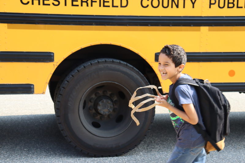 Child smiling in front of school bus