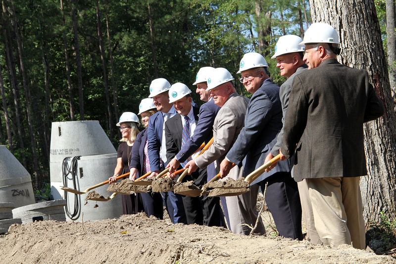 Adults in hard hats holding shovels of dirt