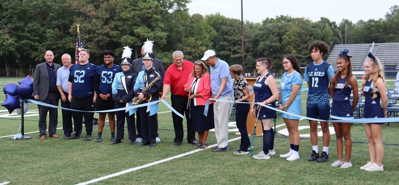 Officials with athletes cutting ribbon